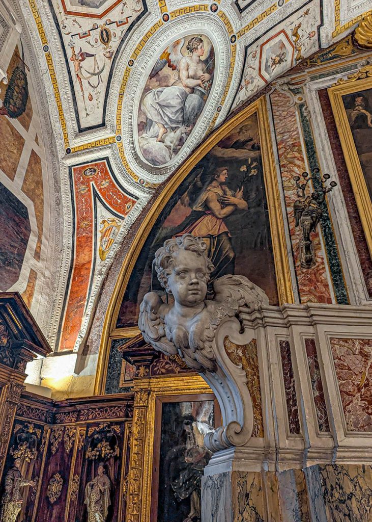 Un putto all'altare e un dettaglio dell'affresco di Giorgio Vasari nella sagrestia a Sant'Anna dei Lombardi a Napoli. Foto sul blog di viaggi "Nerd in Spalla: viaggiatori poco seri".